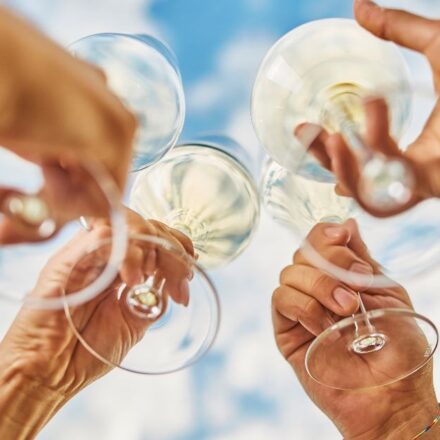 Four glasses of white wine doing a cheers