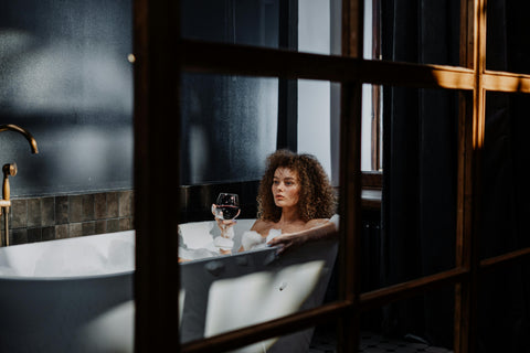 Woman holding wine glass in bubble bath