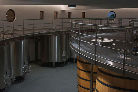 Large wine tanks in winery with stainless steel cat walk above